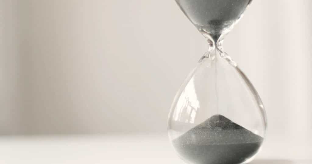Modern hourglass in running time on a grey background